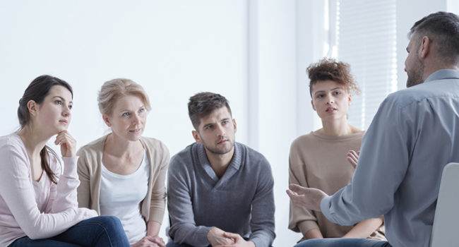 Support group sitting in circle while man confiding his problems